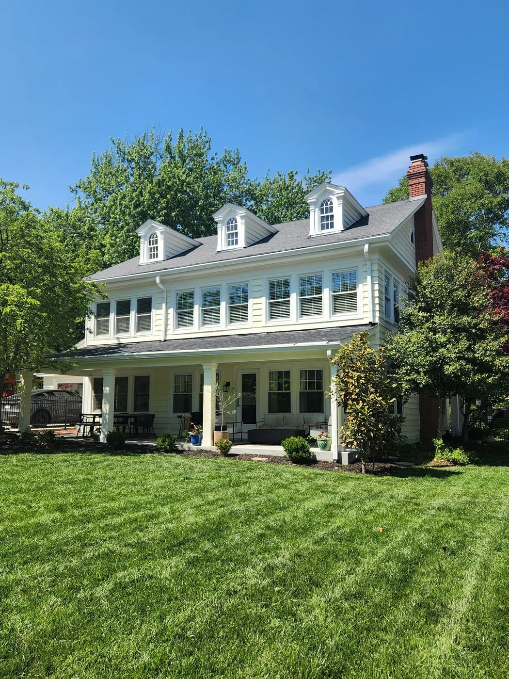 Finished pale yellow house exterior with white window trim, dormers, and porch columns